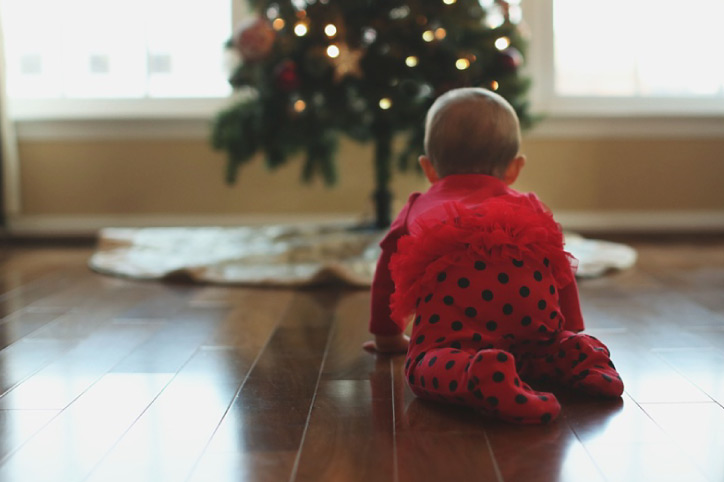 baby crawling on a wood floor toward the Christmas tree