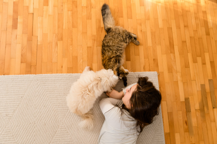 woman on a hardwood floor with her two pets